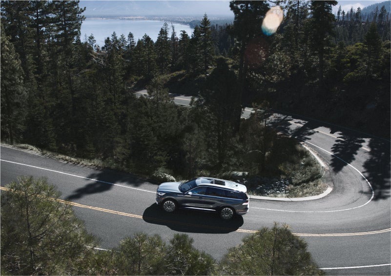 A 2023 Lincoln Aviator® SUV is being driven on a winding mountain road | Karl Malone Lincoln in El Dorado AR